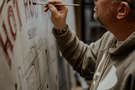 Skiltemaler Sørensen maler detaljer og skygger på et håndmalet Hot Rod TV-skilt.