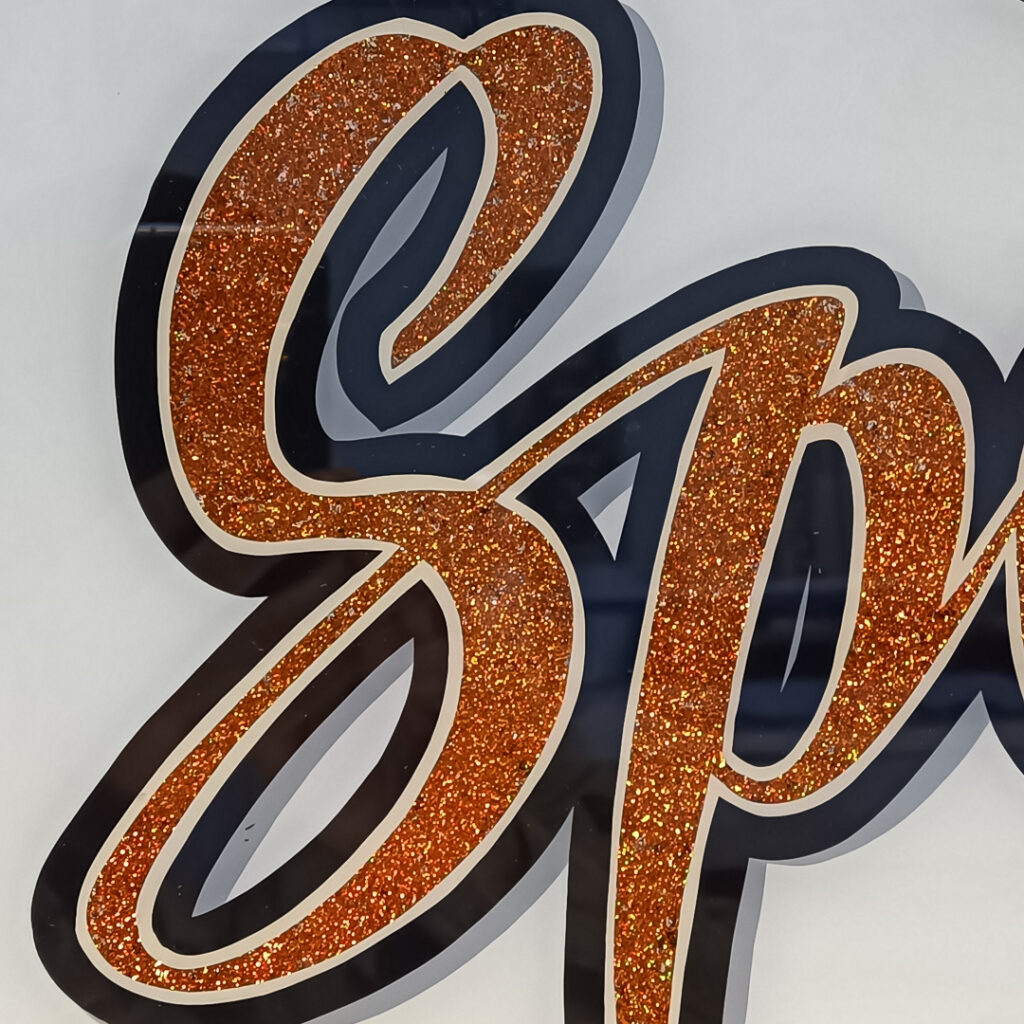 Et detaljeret og personligt specialskilt med glittereffekt, håndmalet for at fremhæve både karakter og dybde i logoet. Her kombineres traditionelt håndværk med moderne udtryk, helt uden brug af maskiner.